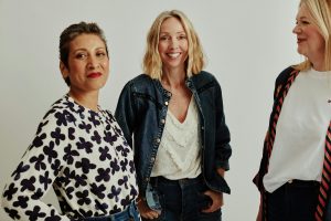 A photo of three women all smiling at the camera looking relaxed and supported.